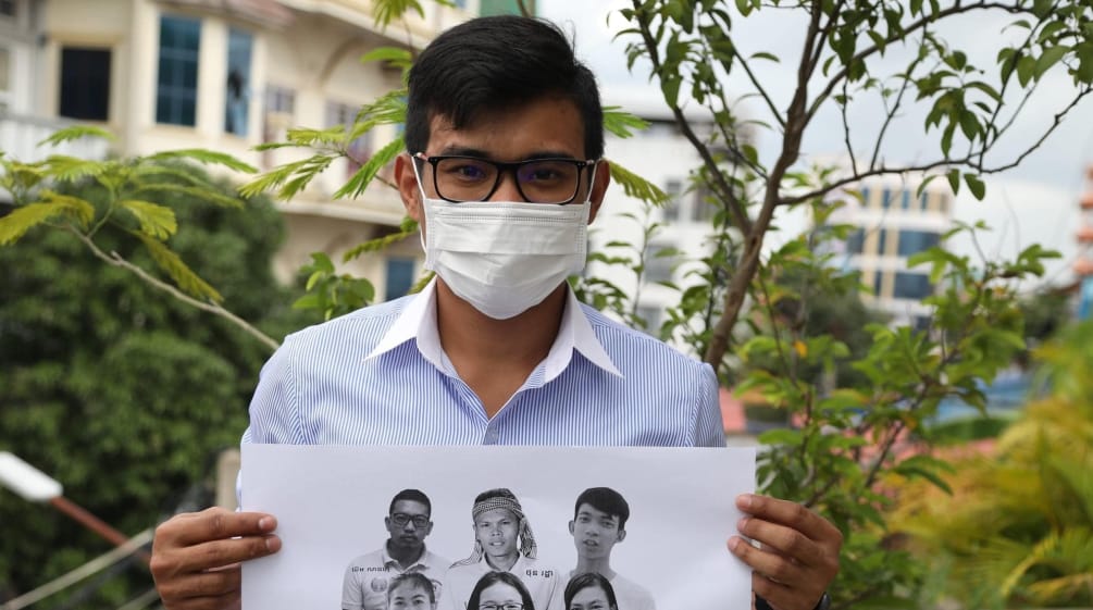 Un giovane tiene in mano un volantino con le foto dei 6 attivisti di Mother Nature imprigionati