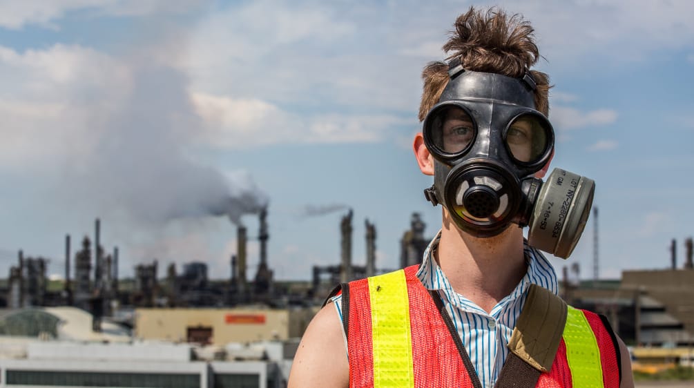 Un uomo protesta con una maschera antigas contro l'estrazione delle sabbie bituminose in Canada.